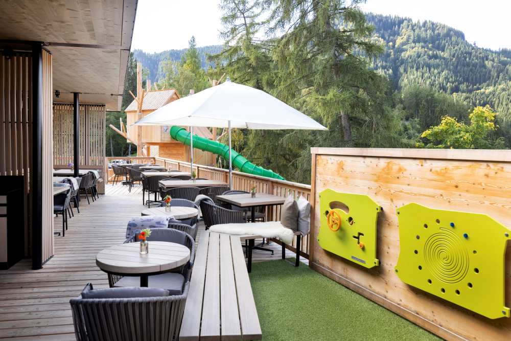 Terrasse des Restaurants mit Blick auf die Rutsche und Spielbereich für Kleinkinder durch an der Wand befestigte Formen und Figuren