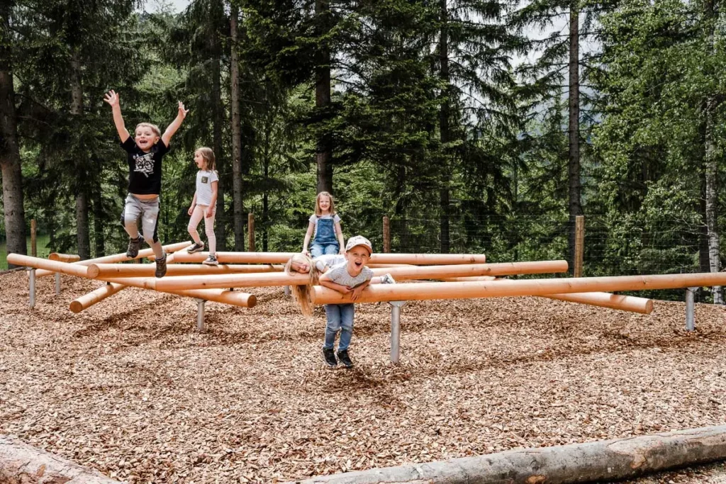 vier Kindergartenkinder beim Spielen im Freizeitpark auf Holzstangen