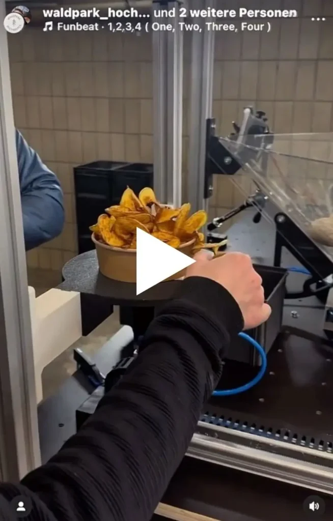 Startbild für Video zur neuen Chips-Maschine im Waldpark 2025: Eine Hand ist zu sehen die die frittierten gekringelten Kartoffeln aus de Roboter entnimmt.