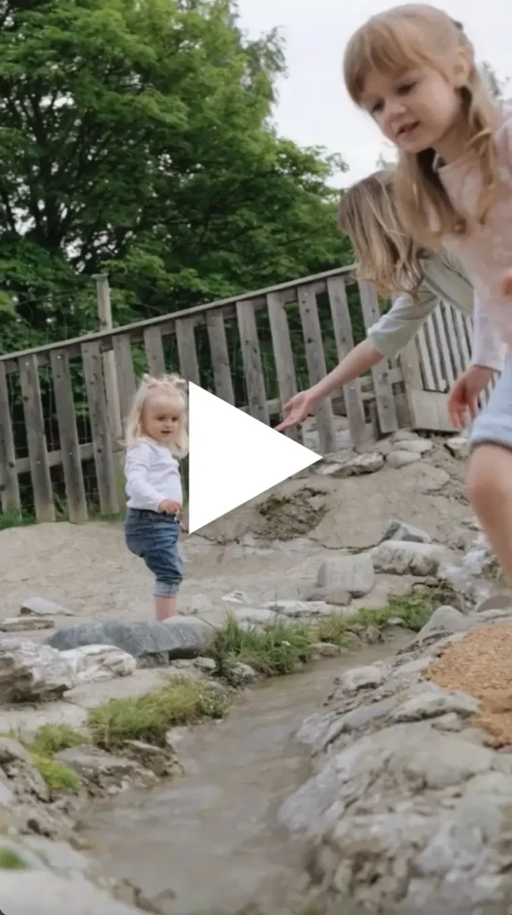 Thumbnail für Video zu Wasserspielplatz Waldpark Hochreiter - am Bild sind Mädchen am Wasserlauf mit kurzen Hosen